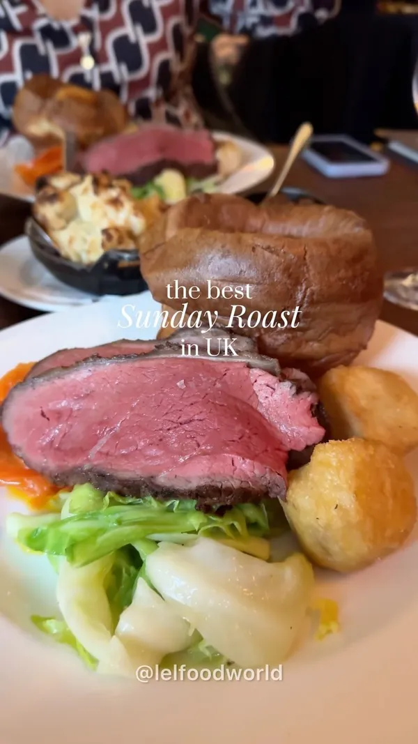 The video showcases Hawksmoor restaurant's Sunday roast. It features various dishes, including roast beef with Yorkshire puddings, roasted potatoes, cauliflower cheese, and a selection of side vegetables. The setting is a high-end restaurant with a sophisticated ambiance. The food presentation is visually appealing, emphasizing high quality ingredients and elegant plating. The video focuses on the meal itself, highlighting the attractive presentation and the overall dining experience.